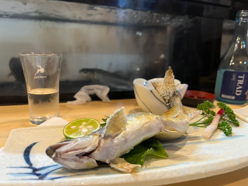 A charcoal grilled japanese freshwater ayu trout plated with sea salt and sodachi citrus